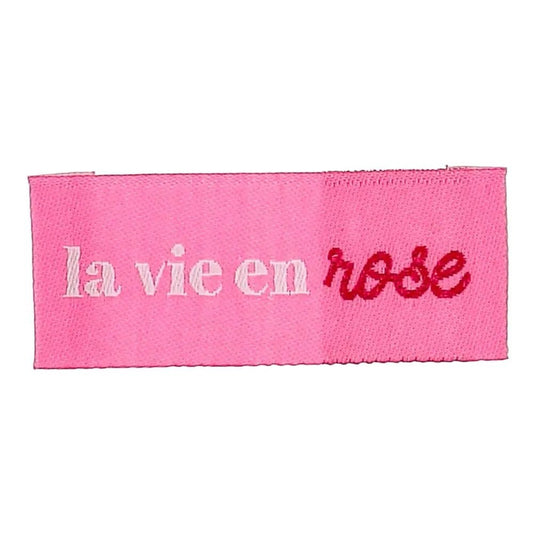 Kuva Bohin-ommeltavasta vaate-etiketistä ”La vie en rose” – katsoa elämää ruusunpunaisten lasien läpi – 2 × 5 cm, 4 kpl – saatavilla verkossa Šarlotes audumi