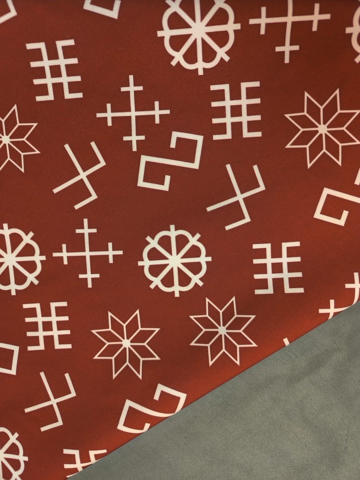 Tissu softshell - avec des symboles de force lettons sur fond brun rouge 310 g/m²